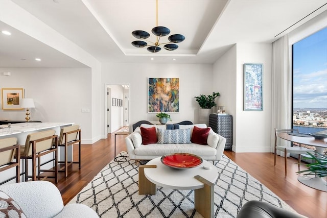 living room with dark wood-type flooring and a tray ceiling