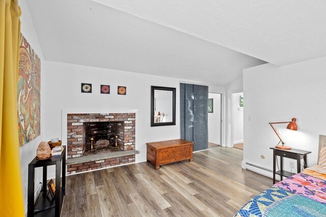 2 Cushing Lndg, Scituate, MA 02066 - bedroom with a baseboard radiator, vaulted ceiling, wood finished floors, and a brick fireplace