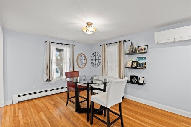 dining space with a baseboard radiator, light hardwood / wood-style floors, and an AC wall unit