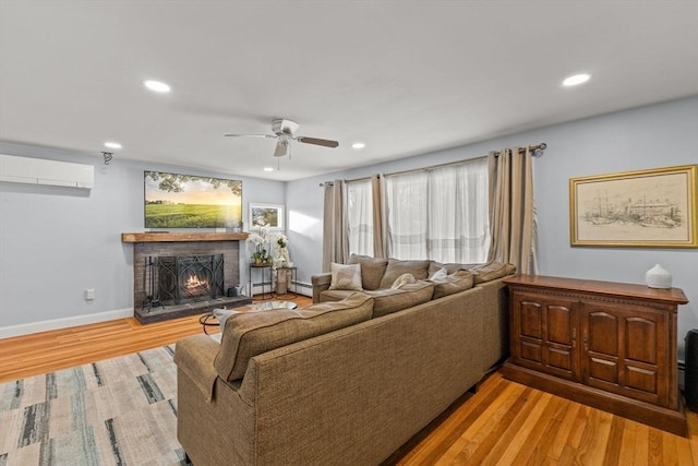 living room featuring an AC wall unit, ceiling fan, and light wood-type flooring