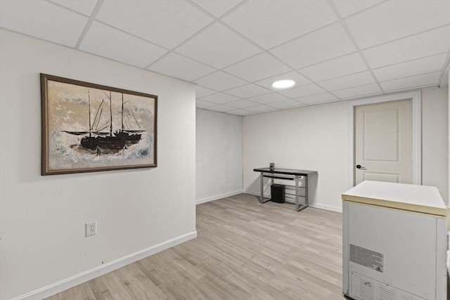 basement with refrigerator, light hardwood / wood-style floors, and a drop ceiling