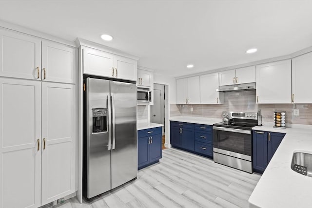 kitchen featuring blue cabinets, white cabinetry, stainless steel appliances, light hardwood / wood-style floors, and backsplash