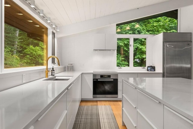 86 Myles Standish Rd, Weston, MA 02493 - kitchen with stainless steel appliances, a sink, light countertops, light wood-style floors, and white cabinets