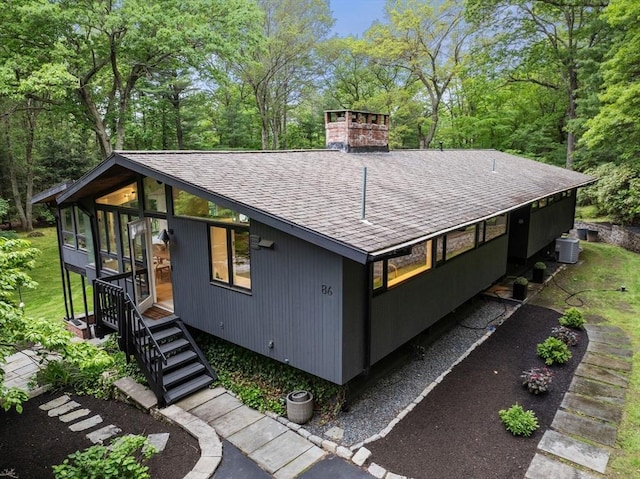 86 Myles Standish Rd, Weston, MA 02493 - view of side of property with roof with shingles, central air condition unit, a chimney, and view of scattered trees