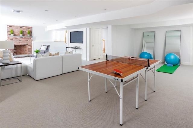 game room with a brick fireplace and light colored carpet