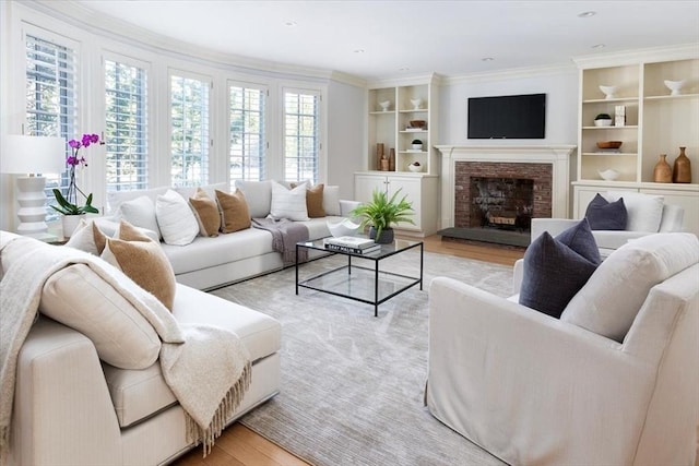 living room featuring light hardwood / wood-style floors, crown molding, and a stone fireplace