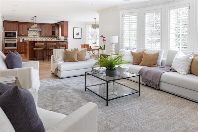 living room with a healthy amount of sunlight, crown molding, and light hardwood / wood-style flooring