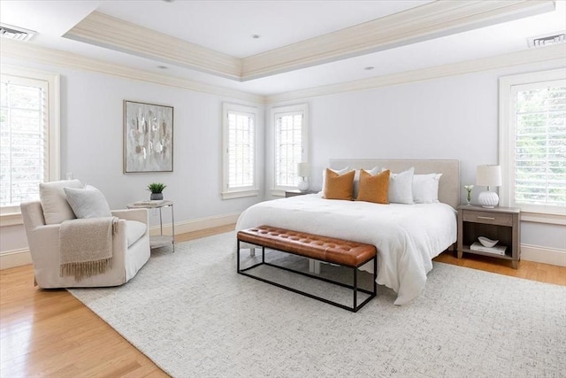 bedroom with hardwood / wood-style flooring, a tray ceiling, and crown molding