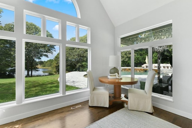 sunroom / solarium featuring lofted ceiling, a healthy amount of sunlight, and a water view