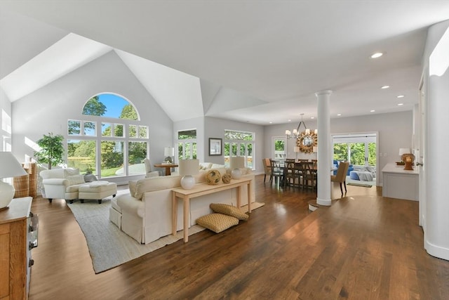 living room featuring lofted ceiling, dark hardwood / wood-style flooring, an inviting chandelier, and decorative columns