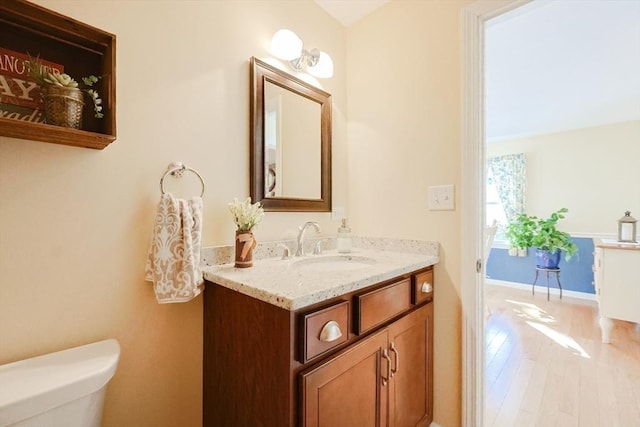 bathroom with hardwood / wood-style flooring, vanity, and toilet