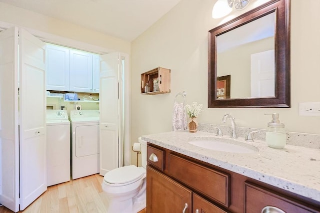 bathroom with toilet, vanity, hardwood / wood-style floors, and separate washer and dryer