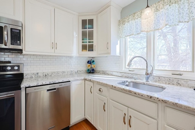 kitchen with stainless steel appliances, decorative light fixtures, sink, tasteful backsplash, and white cabinets