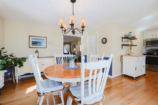 dining space with light hardwood / wood-style flooring and a chandelier