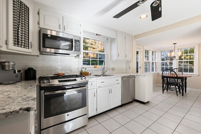 kitchen featuring white cabinetry, tasteful backsplash, light tile patterned flooring, ceiling fan with notable chandelier, and appliances with stainless steel finishes