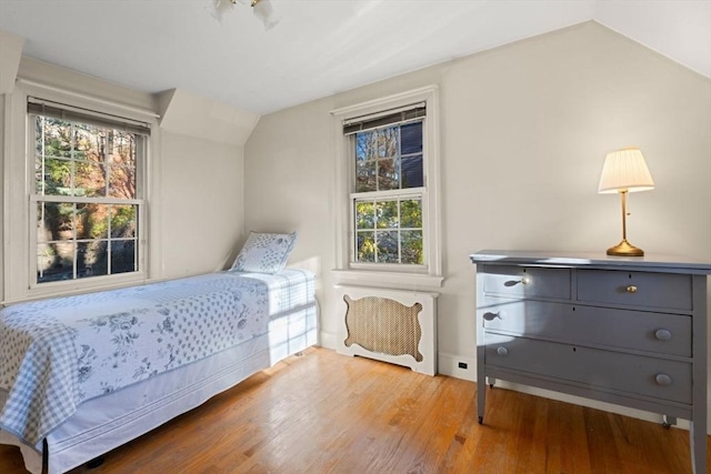 bedroom featuring hardwood / wood-style flooring, lofted ceiling, and multiple windows