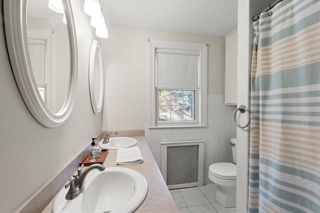 bathroom with vanity, tile patterned flooring, toilet, tile walls, and radiator heating unit