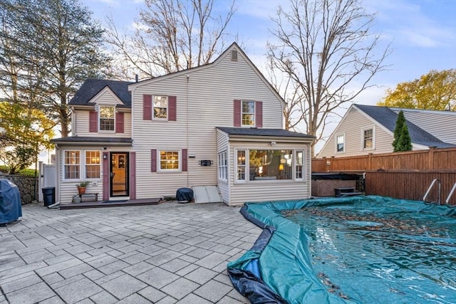 back of property with a swimming pool with hot tub and a patio area