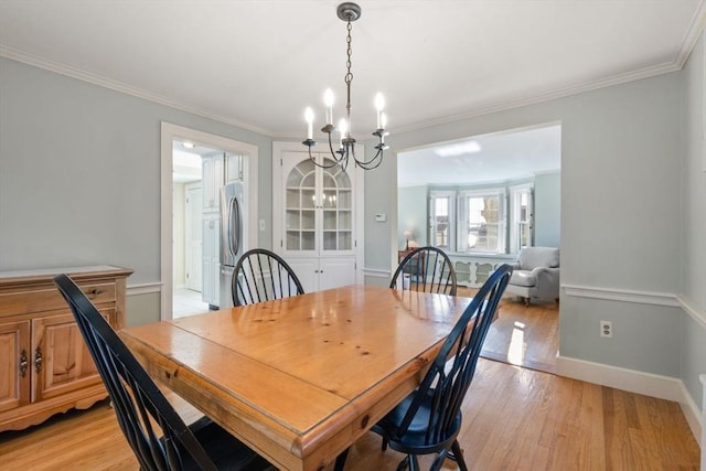 dining space with a notable chandelier, crown molding, and light hardwood / wood-style flooring