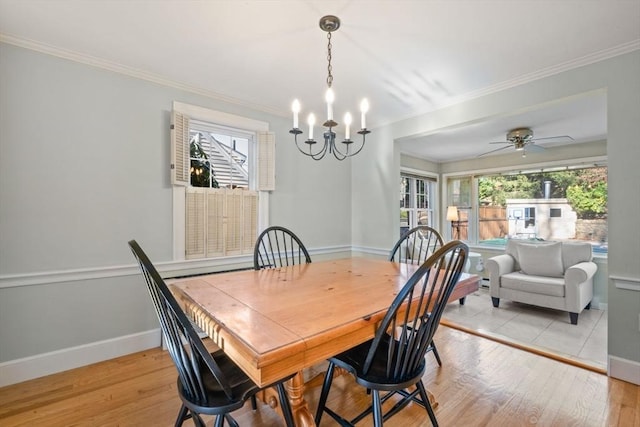 dining space with light wood-type flooring, ceiling fan with notable chandelier, plenty of natural light, and crown molding