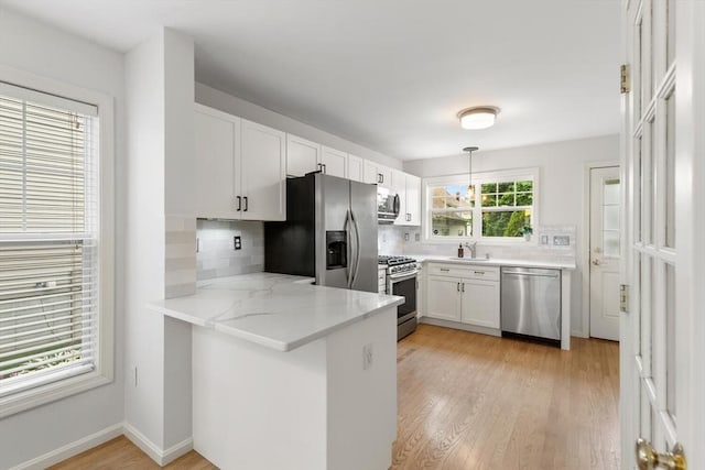 32 Pearl St Unit 32, Everett, MA 02149 - kitchen featuring appliances with stainless steel finishes, a peninsula, decorative backsplash, white cabinets, and light wood finished floors