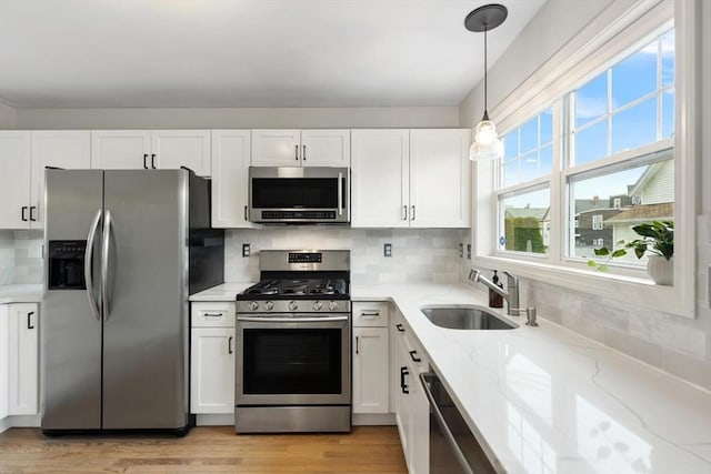 32 Pearl St Unit 32, Everett, MA 02149 - kitchen featuring appliances with stainless steel finishes, light stone countertops, white cabinets, decorative backsplash, and light wood-type flooring