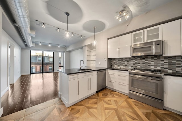 kitchen featuring sink, stainless steel appliances, kitchen peninsula, decorative light fixtures, and white cabinets