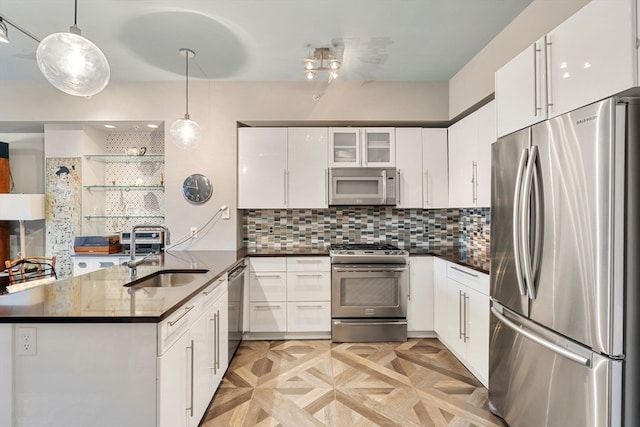 kitchen featuring white cabinets, sink, decorative light fixtures, kitchen peninsula, and stainless steel appliances