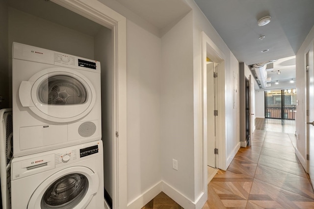 laundry area featuring stacked washer / drying machine and light parquet floors