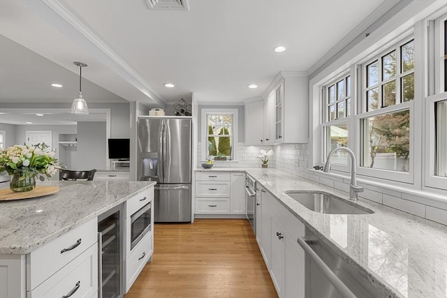 kitchen featuring tasteful backsplash, a sink, stainless steel appliances, ornamental molding, and wine cooler