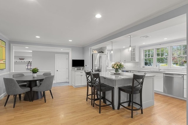 dining space with crown molding, recessed lighting, visible vents, and light wood-type flooring