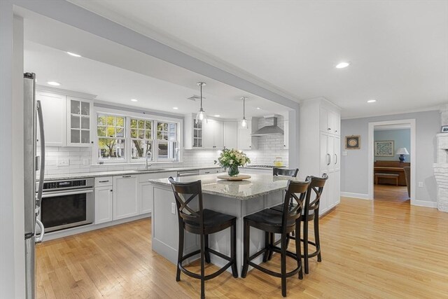 kitchen featuring wall chimney exhaust hood, a sink, tasteful backsplash, and oven