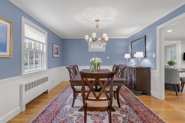 dining room with a chandelier, light wood-type flooring, radiator, and crown molding