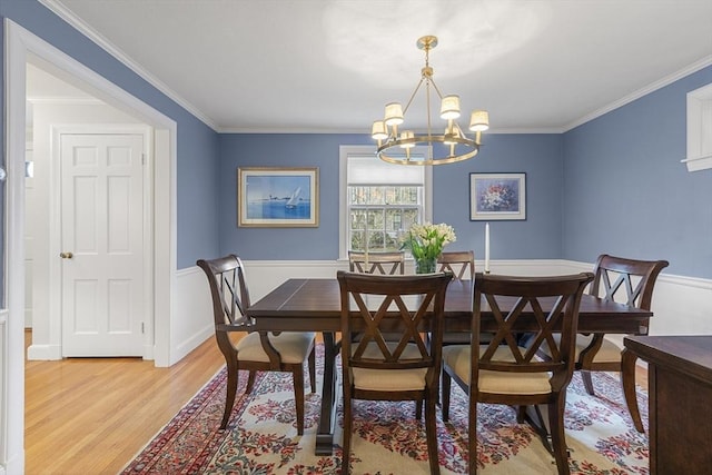 dining space featuring light wood finished floors, ornamental molding, and a notable chandelier
