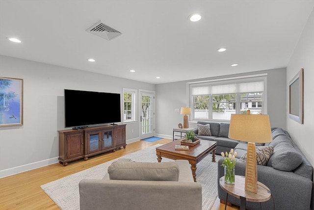 living room featuring baseboards, visible vents, light wood-style flooring, and recessed lighting