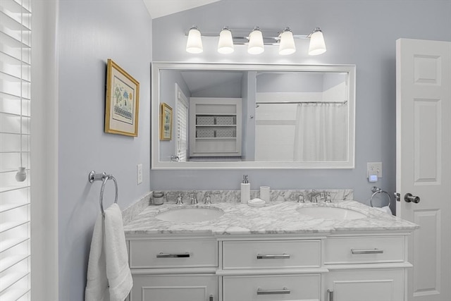 bathroom featuring vaulted ceiling, double vanity, and a sink