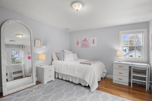 bedroom featuring radiator, visible vents, and wood finished floors