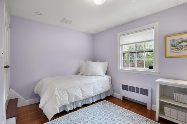 bedroom with baseboards, radiator, and wood finished floors