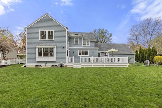 rear view of house with fence, a wooden deck, a yard, and roof with shingles