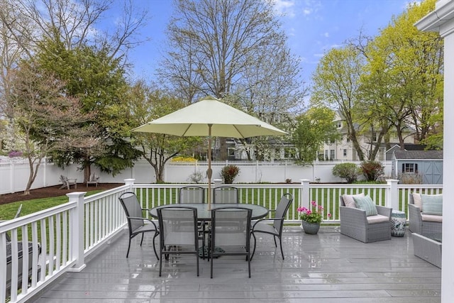 wooden deck featuring an outbuilding, a fenced backyard, a lawn, a shed, and outdoor dining space
