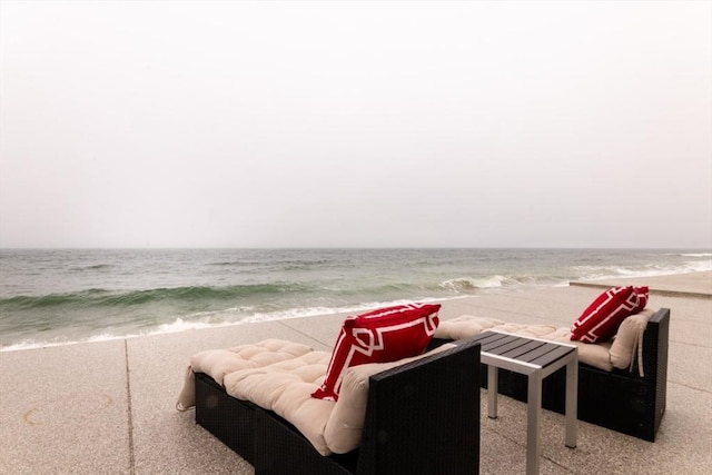 view of patio with a water view and a beach view