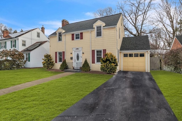 view of front of property featuring a garage, driveway, a chimney, and a front yard