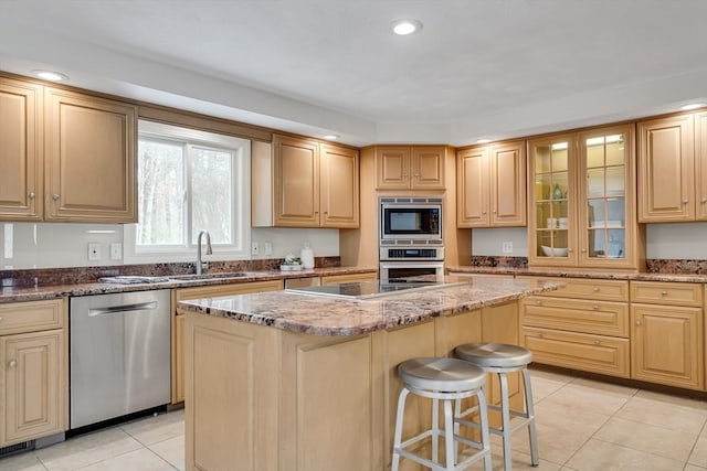 kitchen featuring a breakfast bar, sink, a center island, stainless steel appliances, and light stone countertops