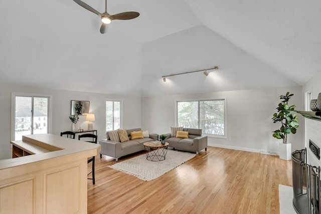 living room with ceiling fan, vaulted ceiling, and light wood-type flooring