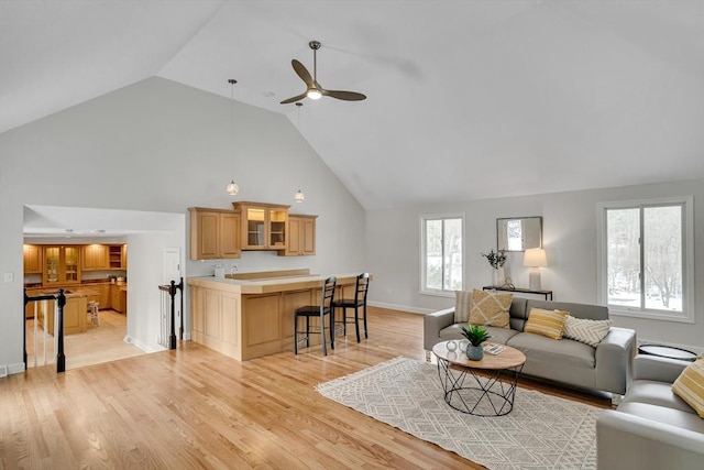 living room with ceiling fan, high vaulted ceiling, and light hardwood / wood-style floors