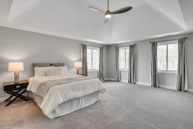 carpeted bedroom featuring ceiling fan and a tray ceiling