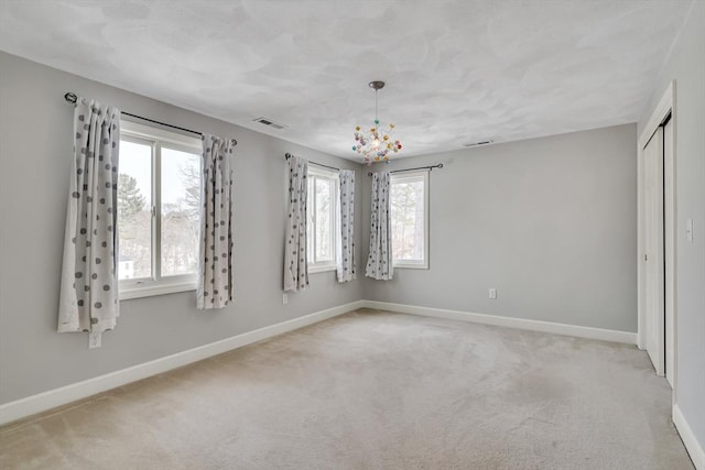 carpeted spare room featuring a chandelier