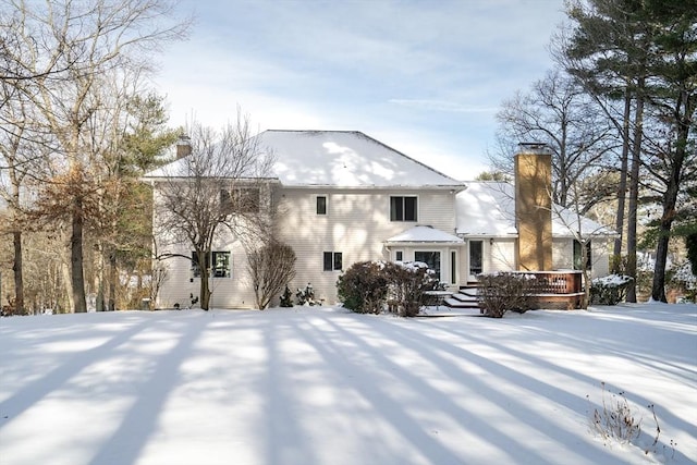 snow covered back of property with a wooden deck