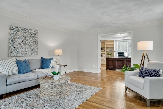 living room featuring built in shelves, ornamental molding, and light hardwood / wood-style flooring