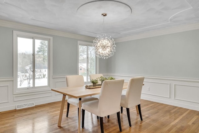 dining area featuring an inviting chandelier, crown molding, and light hardwood / wood-style flooring